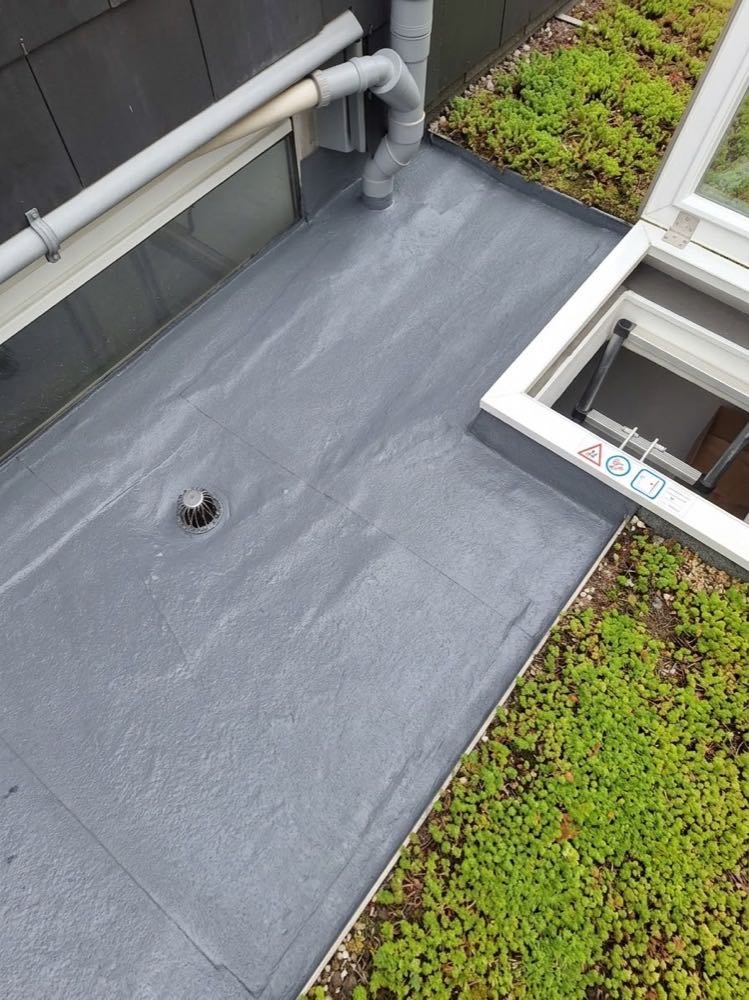 Roofing fraîchement posé par Le Ghost du Débouchage sur une toiture plate, avec évacuation d'eau pluviale intégrée, à côté d'une toiture végétalisée